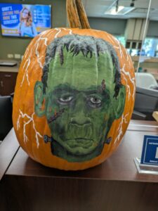orange pumpkin painted with a Frankenstein image with lightning
