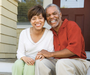 Senior couple sitting on the steps of their front porch